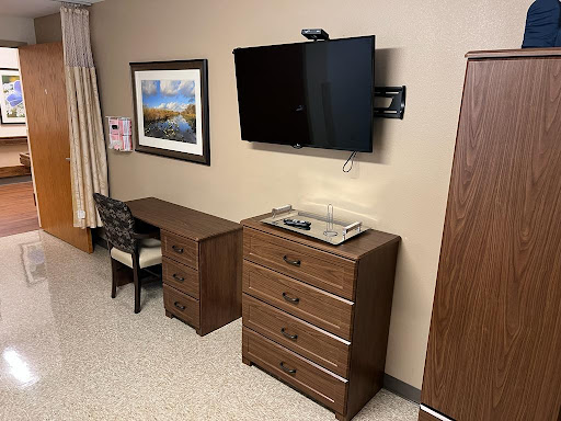 A cozy room setup featuring a television, dresser, and a desk with artwork on the wall.