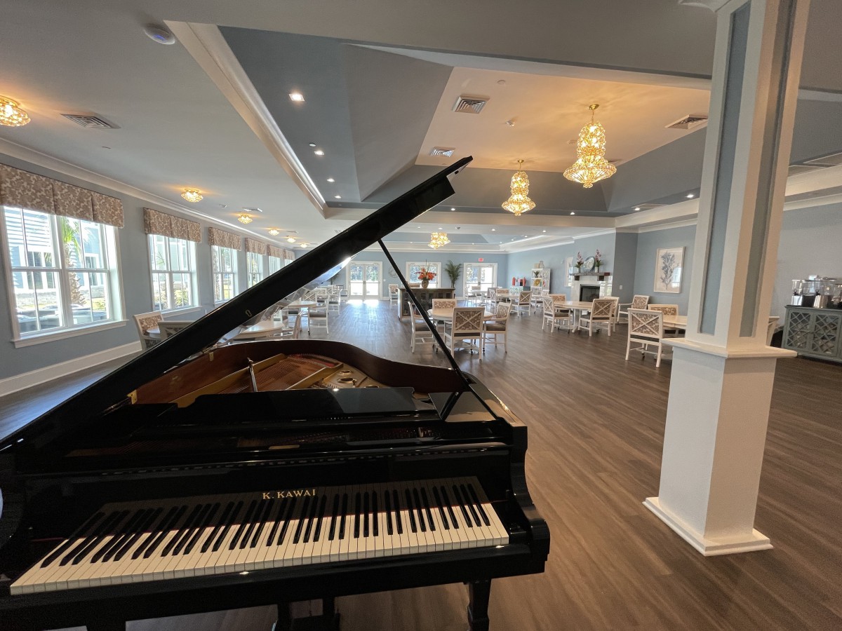 A spacious room with a grand piano and elegant chandeliers.