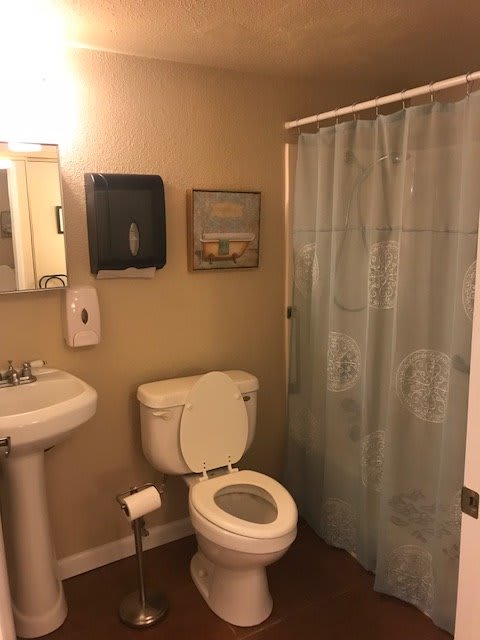 A clean and organized bathroom with a toilet, sink, and shower.