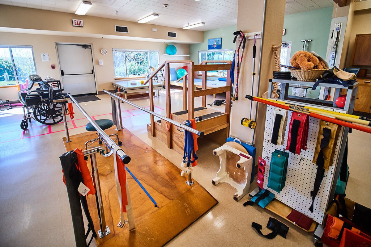 A rehabilitation center equipped with parallel bars and exercise equipment for physical therapy.