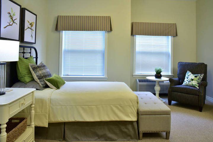 A cozy bedroom with a large bed, neutral decor, and two windows.