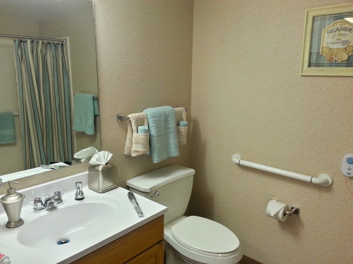 A clean and organized bathroom with a sink, toilet, mirror, and towels.