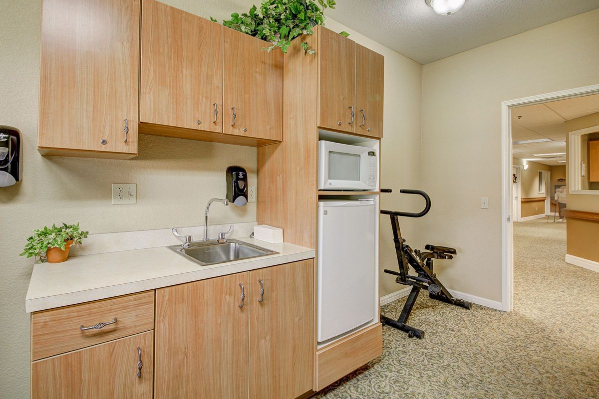 A multipurpose laundry room with wooden cabinets, a sink, and an exercise bike.