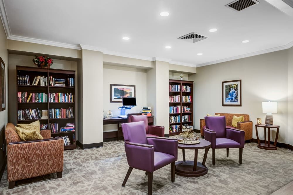 A cozy library space with bookshelves, comfortable chairs, and a computer station.