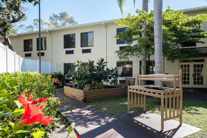 An apartment building with a well-maintained garden and lush greenery on a sunny day.