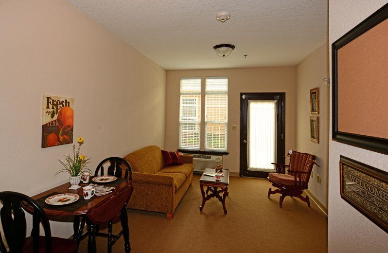 A cozy living room with a sofa, chairs, and a small dining table near a window.