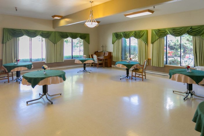 A spacious and quiet indoor seating area with tables and green curtains.