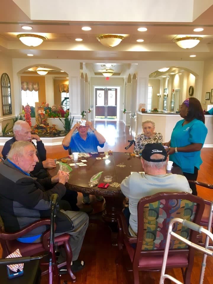 A group of seniors engaging in a conversation with a caregiver at a nursing home.