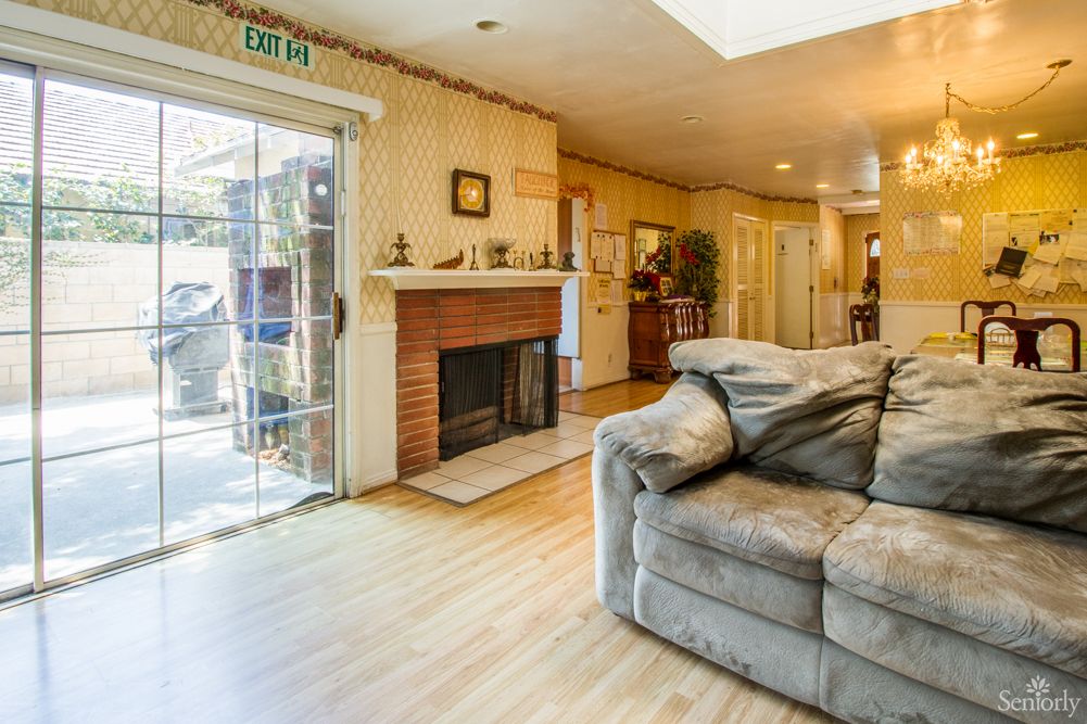 A cozy living room with a fireplace and comfortable couch, featuring wood flooring and a sliding glass door.