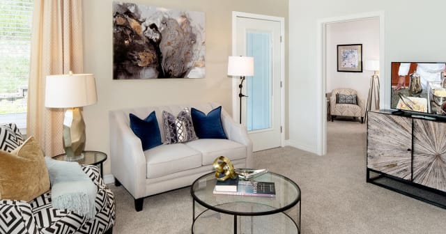 A modern living room with a stylish sofa, decorative pillows, and a glass coffee table.