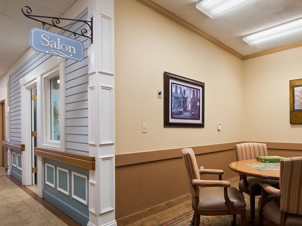A cozy interior space with a salon sign, featuring a table and chairs in a waiting area.