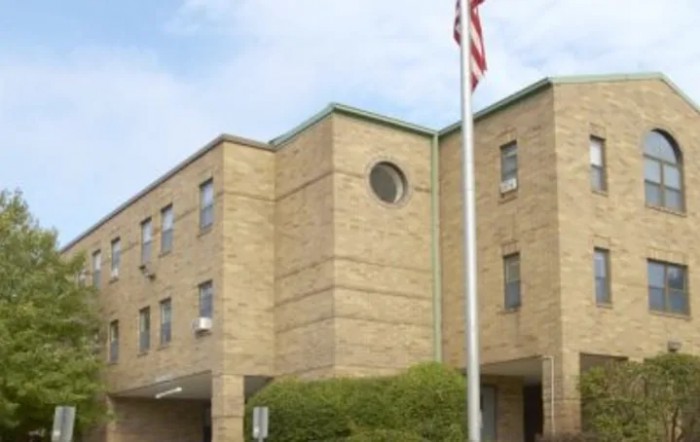 A brick building with an American flag in front on a clear day.