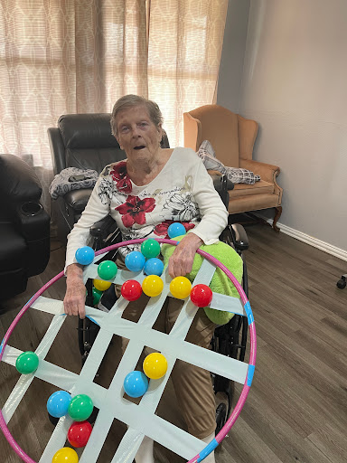 An elderly woman engaged in a colorful activity while sitting in her wheelchair.