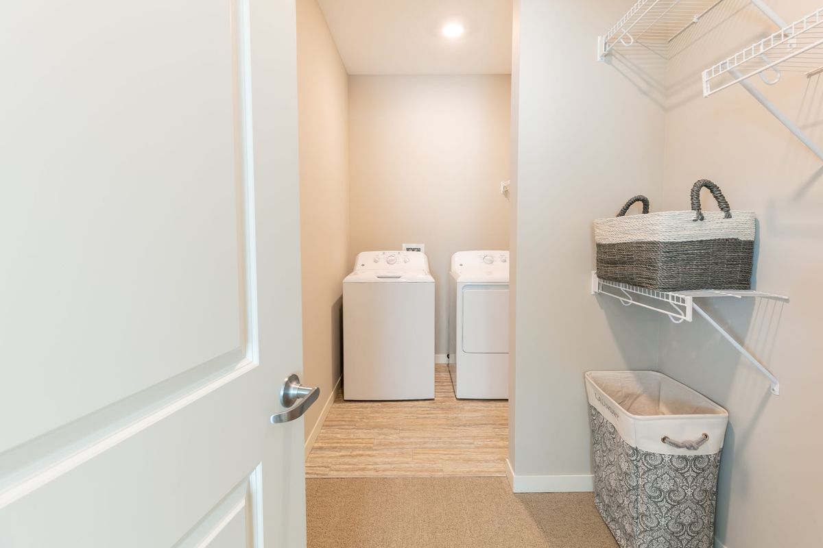 A clean and organized laundry room with a washing machine, dryer, and laundry basket.