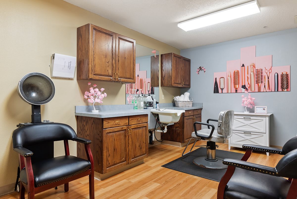 A cozy hair salon interior with wooden cabinets, chairs, and decorative wall art.