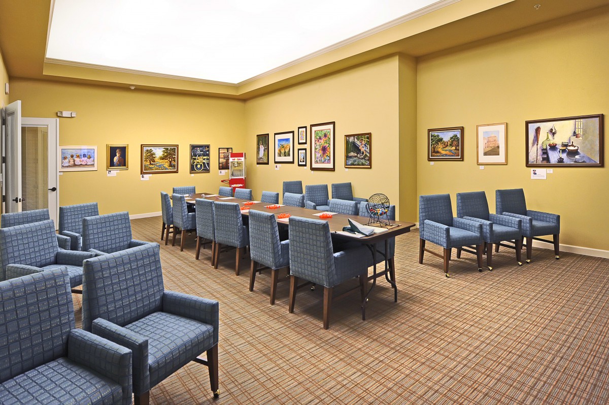 A conference room with a large table, blue chairs, and artwork on the walls.