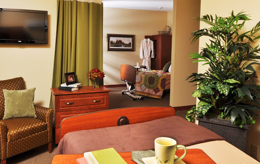 A cozy hospital room featuring a bed, bedside table with a coffee mug, and colorful curtains.