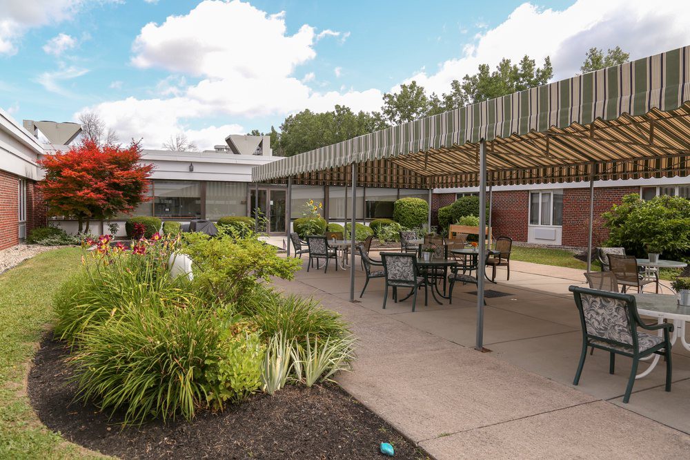 A well-furnished patio area with tables and chairs surrounded by lush greenery.