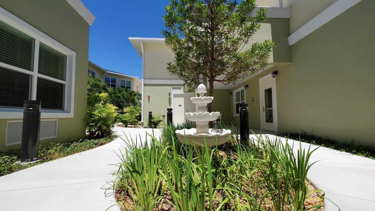 A serene courtyard with a central fountain surrounded by greenery and modern buildings.