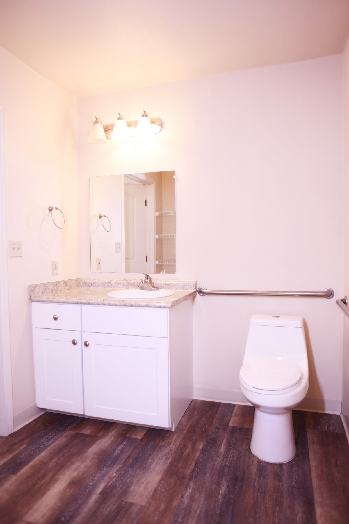 A minimalist bathroom featuring a white vanity with sink, mirror, and toilet.