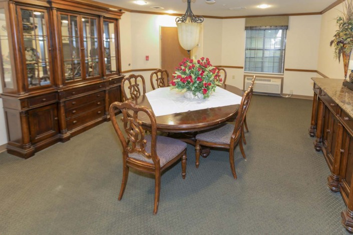 A formal dining room featuring a wooden table with chairs, a chandelier, and a display cabinet.