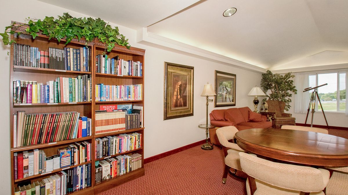 A cozy living room with a large bookshelf, comfortable seating, and decorative artwork on the walls.