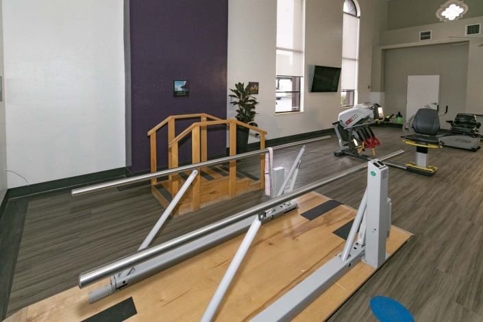 A room equipped for physical therapy with parallel bars and exercise equipment.