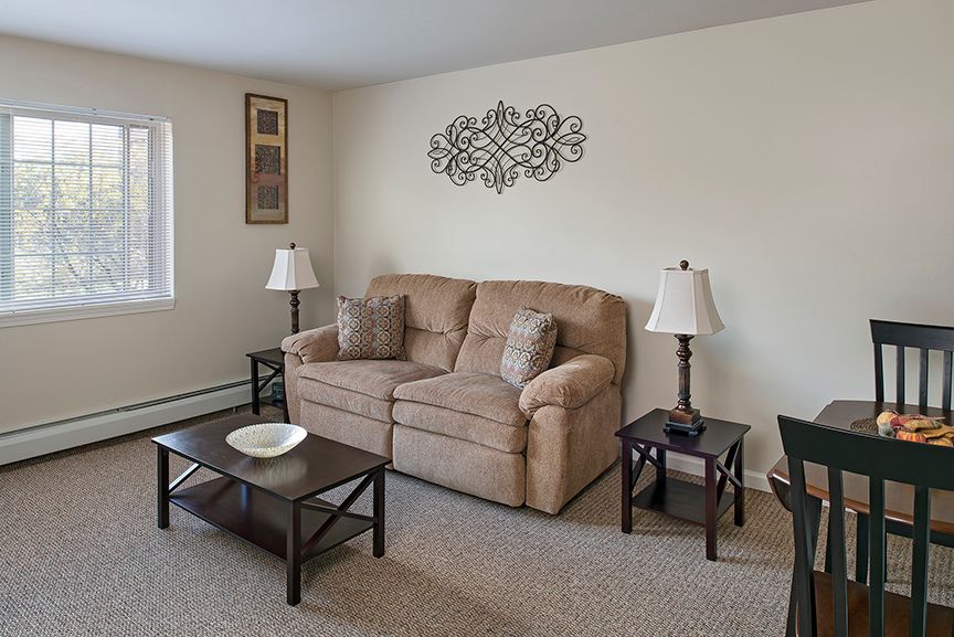 A cozy living room with a beige sofa, two matching end tables and lamps, a coffee table, and decorative wall art.