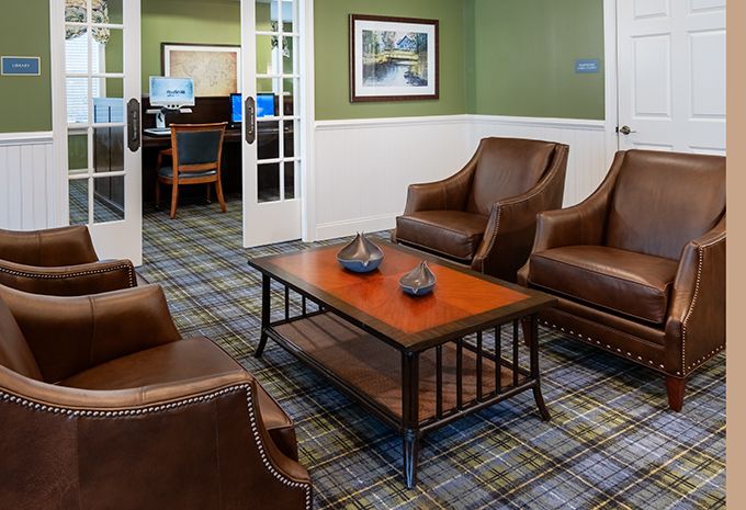 A cozy waiting room with leather chairs and a wooden coffee table, featuring a plaid-patterned carpet.