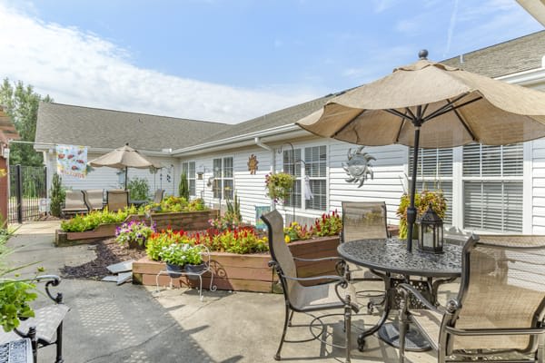 A sunny patio with outdoor furniture, umbrellas, and vibrant flower planters.