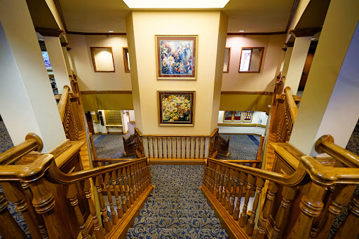 A beautifully designed interior staircase with wooden railings and framed paintings on the wall.