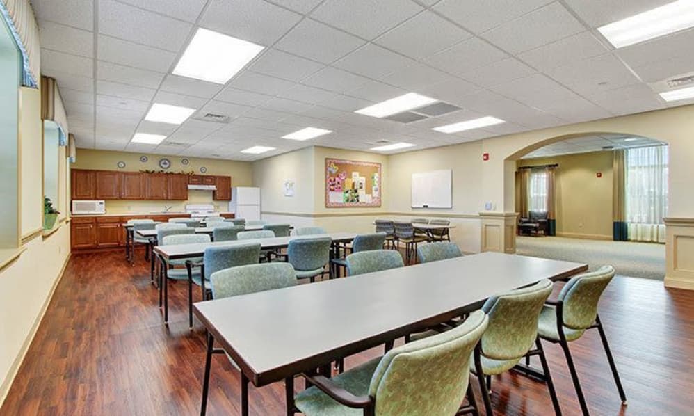 An empty classroom or meeting room with tables and chairs arranged in rows.