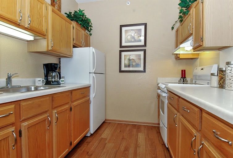 A cozy kitchen with wooden cabinets, featuring a refrigerator, stove, and coffee maker.