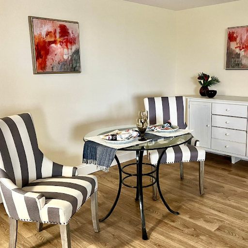 A stylish living room featuring striped chairs, a sleek dining table, and modern artwork.