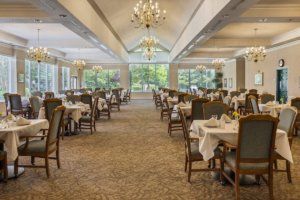 A spacious and elegantly decorated dining room with neatly arranged tables and chairs, adorned with chandeliers.