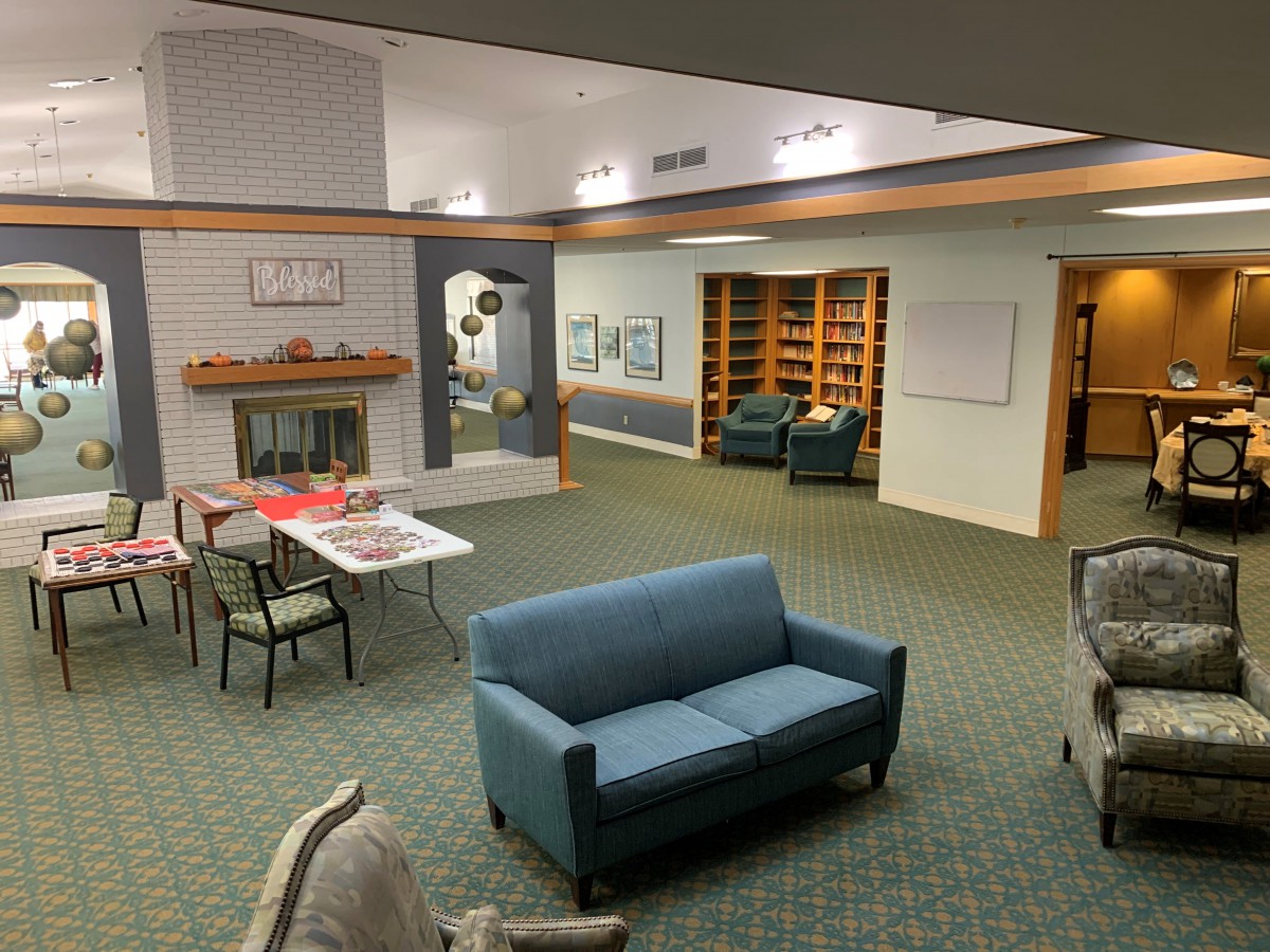 A cozy lounge area with sofas, chairs, a table, and a fireplace, surrounded by bookshelves.