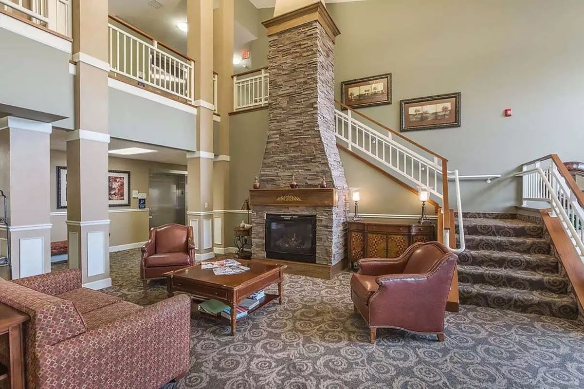 A cozy hotel lobby with a fireplace, seating area, and a staircase.