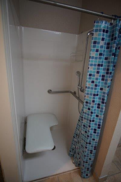 An accessible shower with a bench seat and safety grab bars.