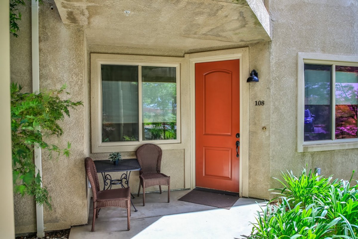 A cozy front porch with a red door and patio furniture.