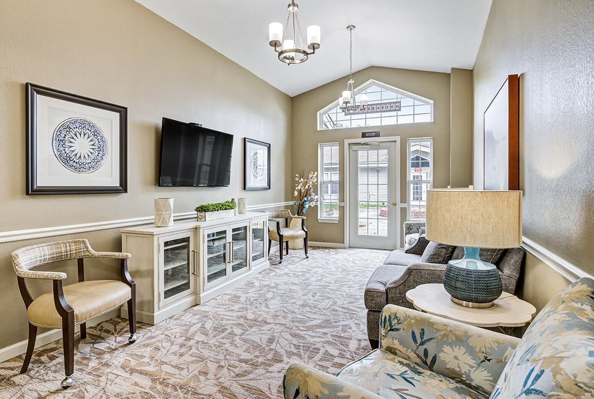 A well-decorated living room with a chandelier, television, and comfortable seating.