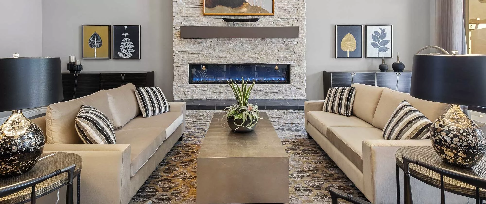 A modern living room featuring a stone fireplace, contemporary sofas, and a sleek coffee table with decorative elements.