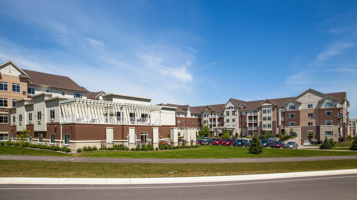 A modern residential housing complex with adjacent parking and landscaped surroundings.