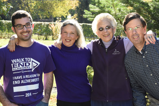 A cheerful group of four people posing together outdoors on a sunny day.