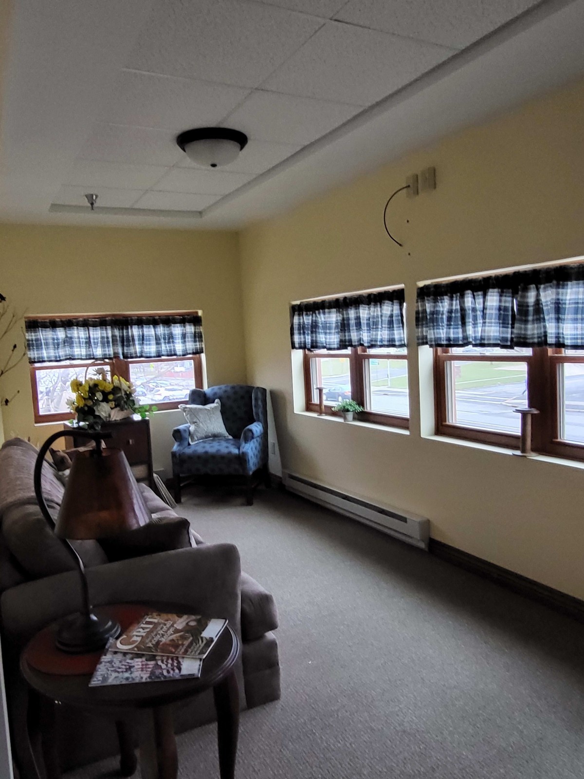 A cozy living room with multiple windows, featuring comfortable seating and simple decor.