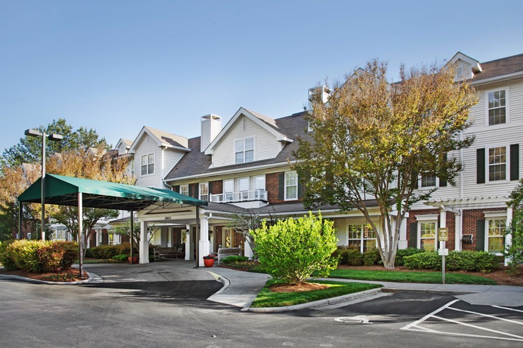 A well-maintained residential building with a covered driveway and landscaped surroundings.