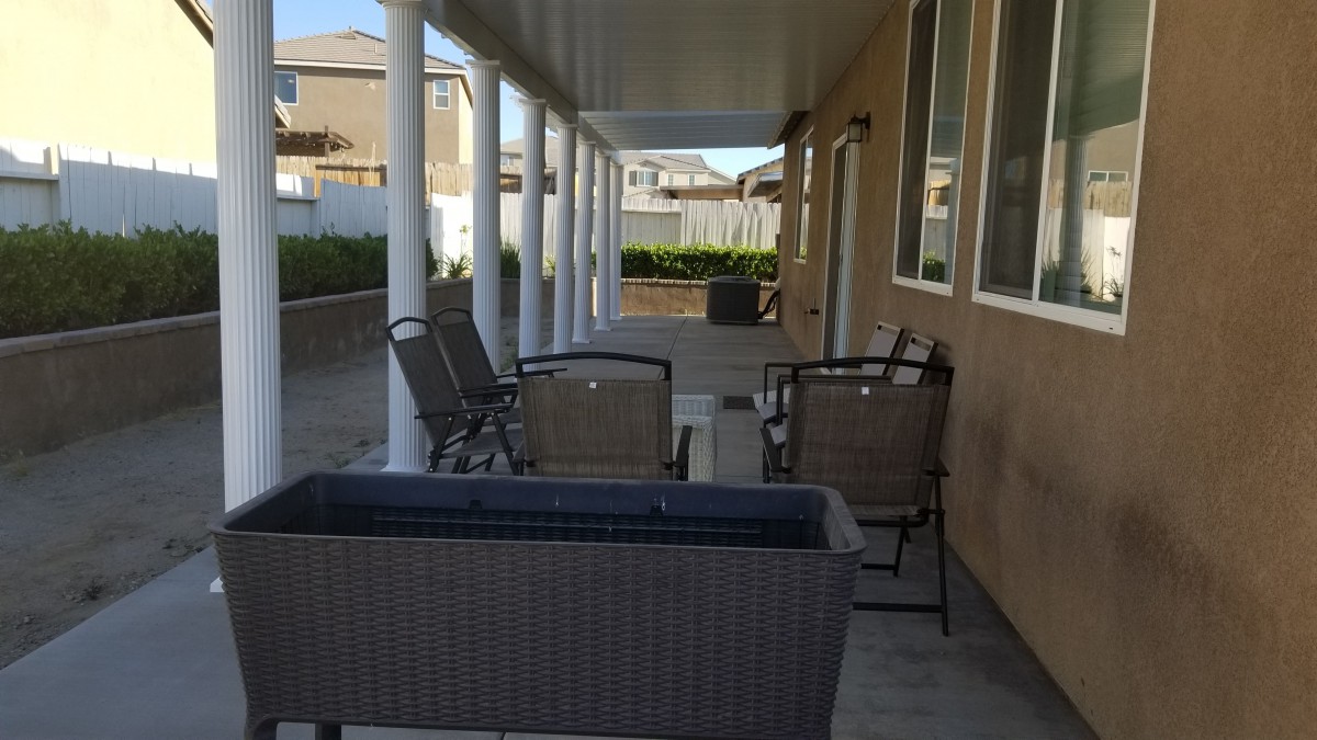A spacious patio area with outdoor furniture and white columns.