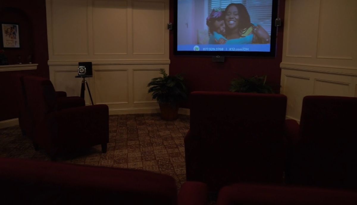 A cozy home theater setup with seating and a projector screen displaying a show.