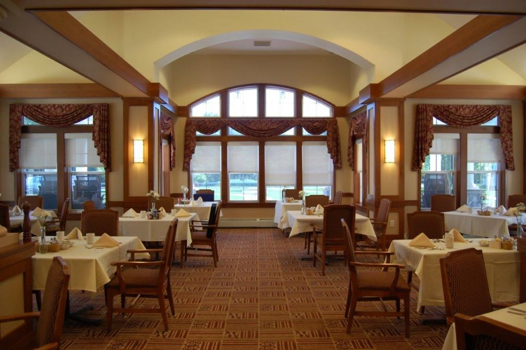An elegant restaurant dining room with neatly set tables and warm lighting.