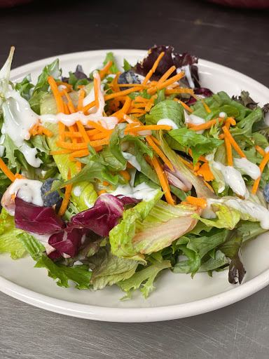 A vibrant and fresh garden salad topped with shredded carrots and a drizzle of dressing.