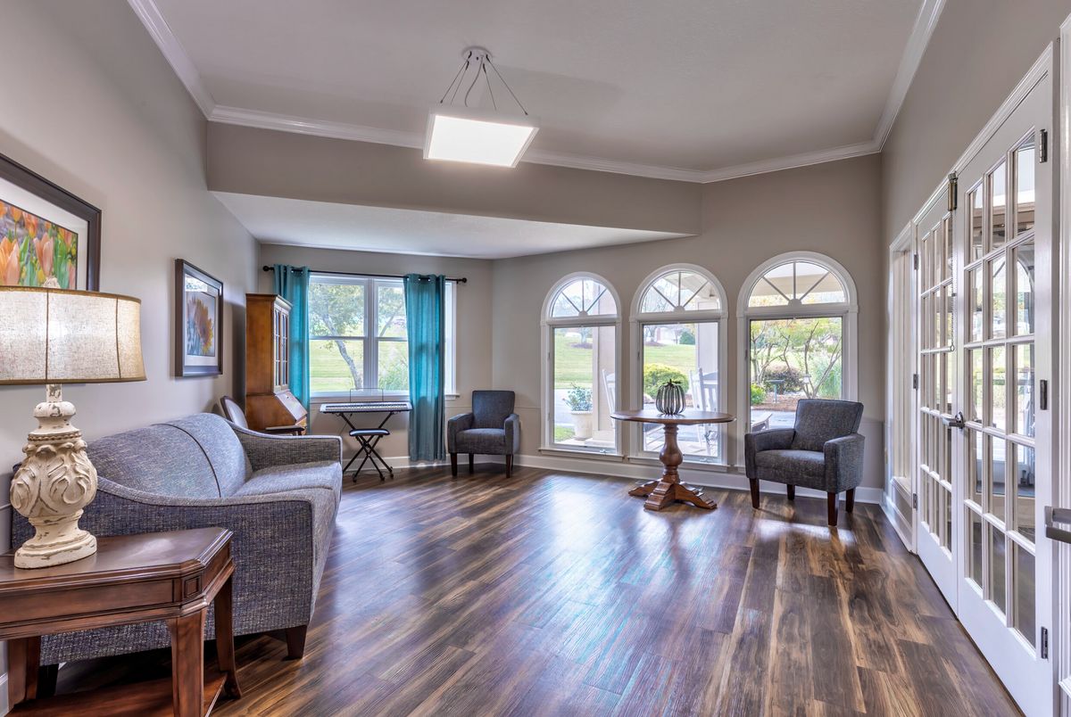 A spacious living room with hardwood floors, modern furniture, and large windows allowing natural light to fill the space.